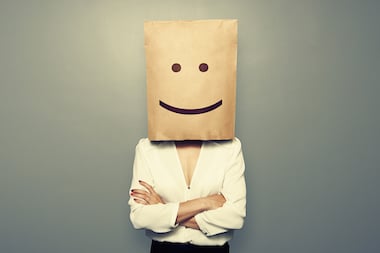 Woman with brown bag over her head with a smiley face on it