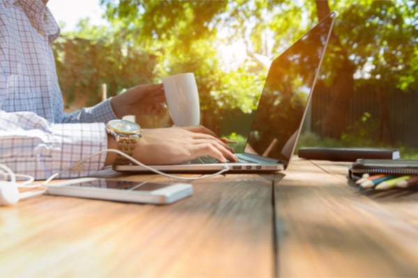 Someone working on a laptop, drinking coffee