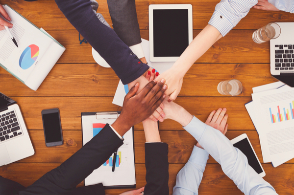 Group of hands joined over a table.