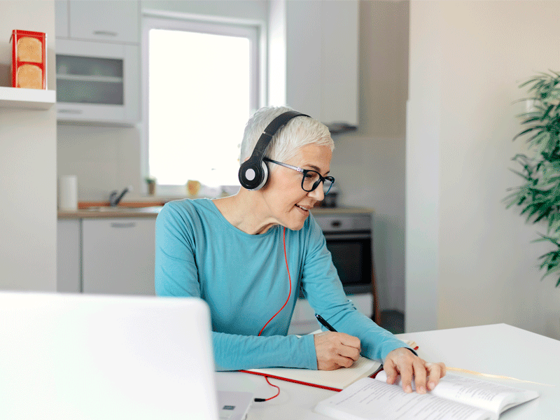 Lady studying remotely at home on laptop with headphones