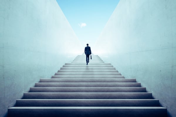 business professional with briefcase climbing stairs to sunlight