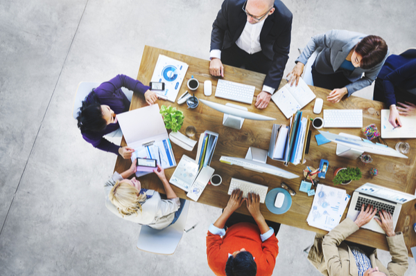 Group of people sitting around a desk with laptops