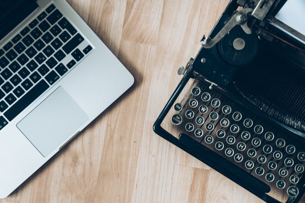 Laptop next to a type writer