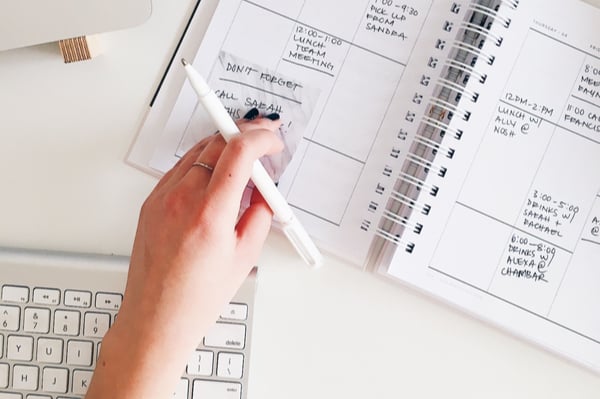 a person placing a post-it note on a diary