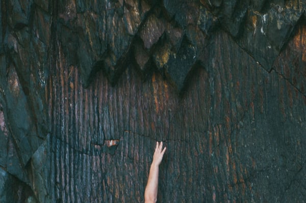 a person raising their hand in front of a textured wall