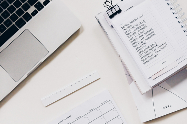 list on a notebook sitting next to a laptop