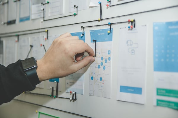 a person pushing a pin into a piece of paper on a board