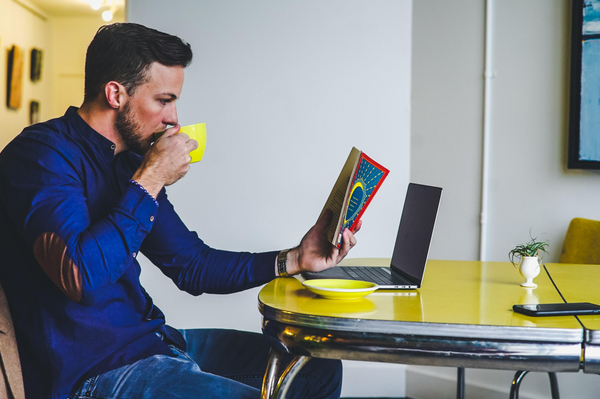 a man drinking from a cup while reading