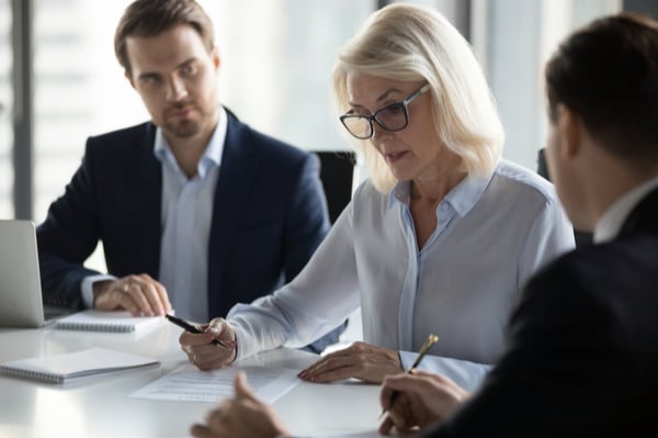 Two men and a woman looking at paper and discussing something