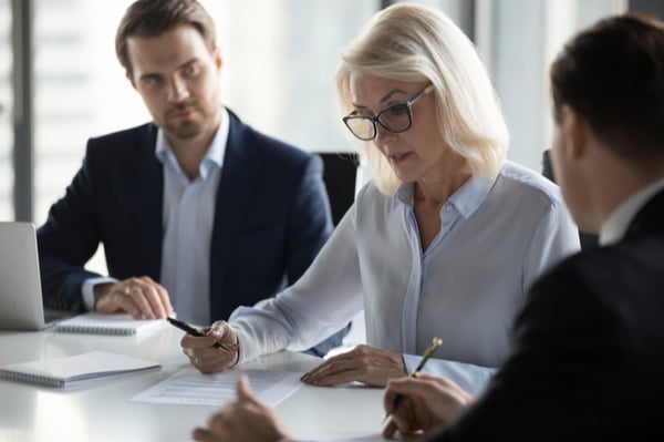 Two men and a woman looking at paper and discussing something