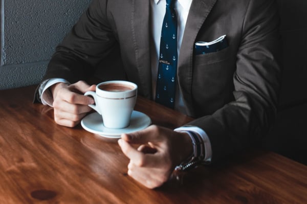 Man in a suit with a small cup of coffe