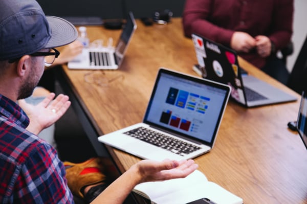 Man with a hat and glasses in front of computer