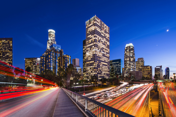 cars speeding along a highway towards a city at night