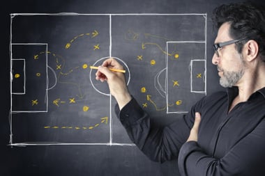 Man drawing a football pitch on a blackboard showing strategy
