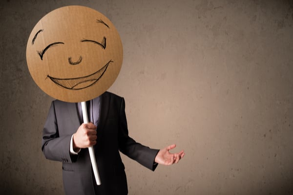 Businessman with hiding his face behind happy face mask
