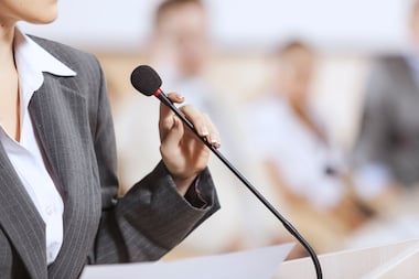 Woman in a suit in front of a microphone