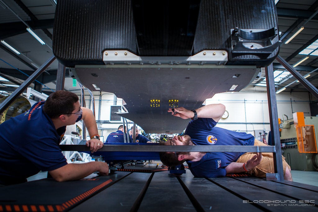 mechanics working on the underside of a car