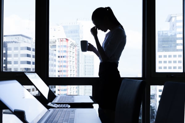 Woman stressed, putting her hand on her head whilst holding a coffee