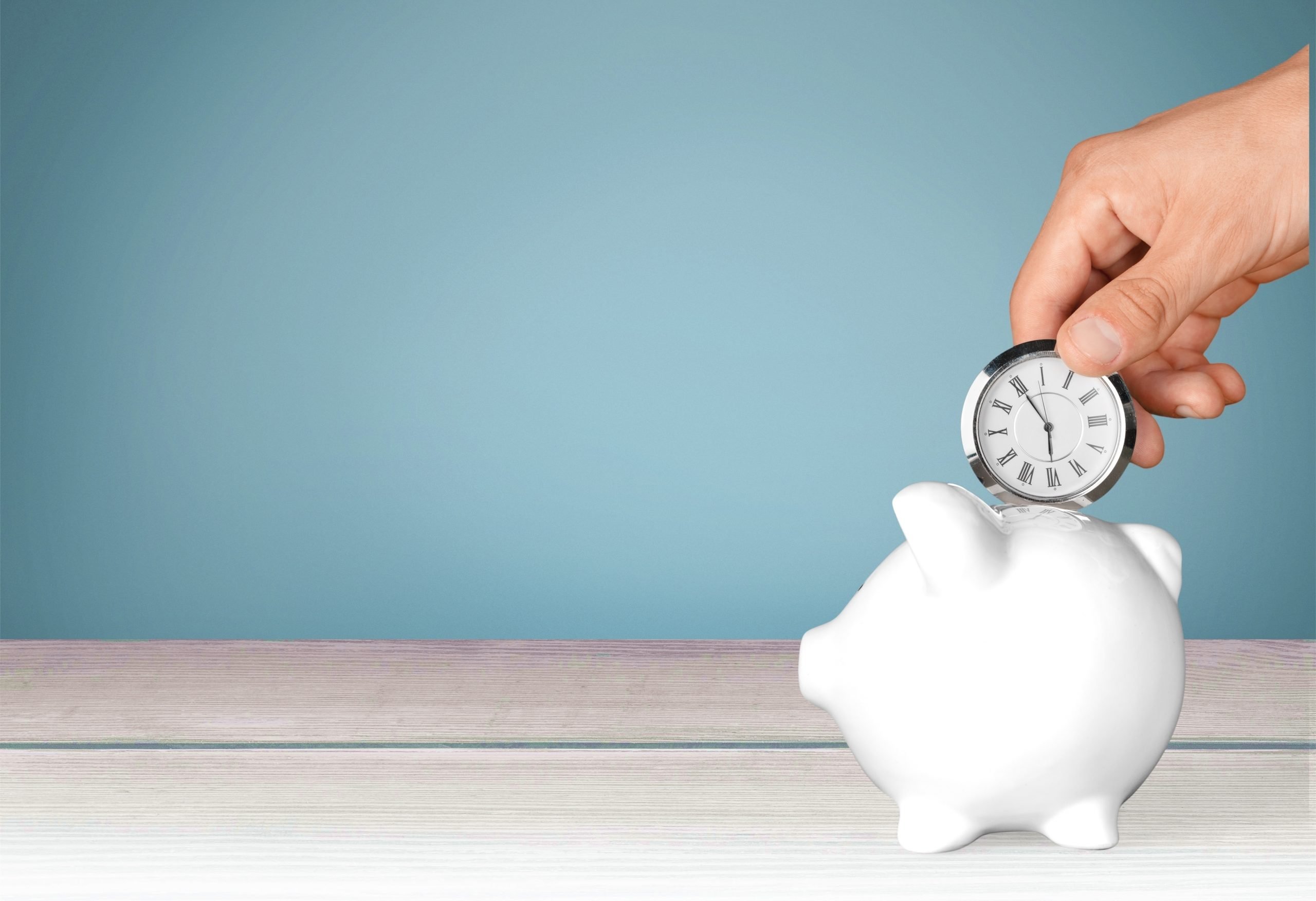 Watch being inserted into a savings piggy bank