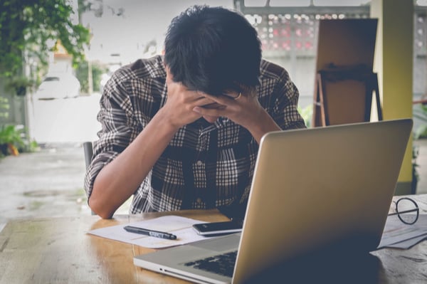 Person holding their head with to hand in front of computer