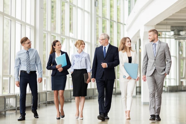 Group of people in suits walking down a hallway