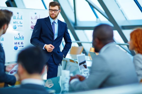 Man in a suit speaking in front of other people