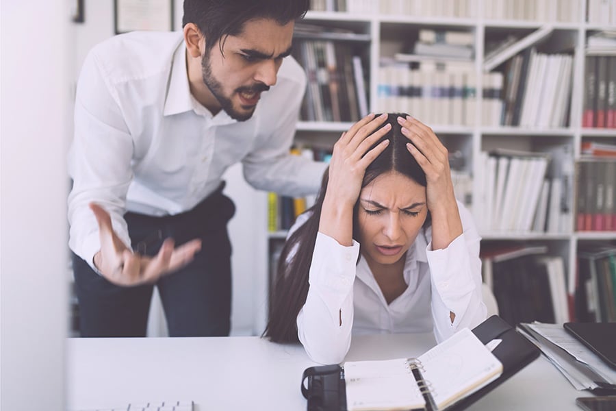 An overbearing boss shouting at someone at a desk