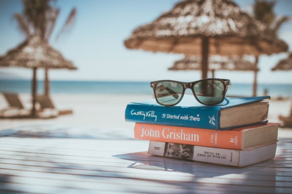 sunglasses resting on a pile of books at the beach