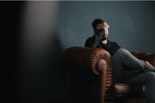 man sitting on a coach holding his head