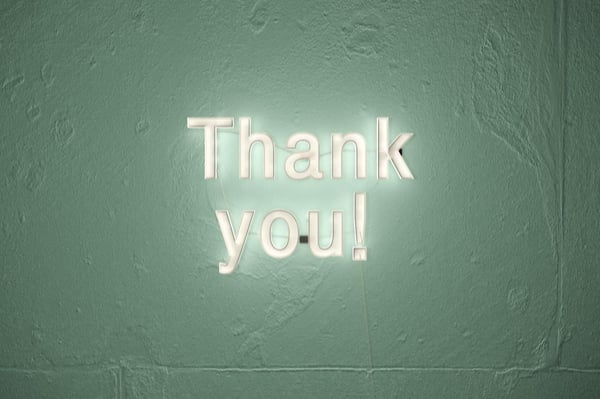 neon type letters on a wall spelling thank you