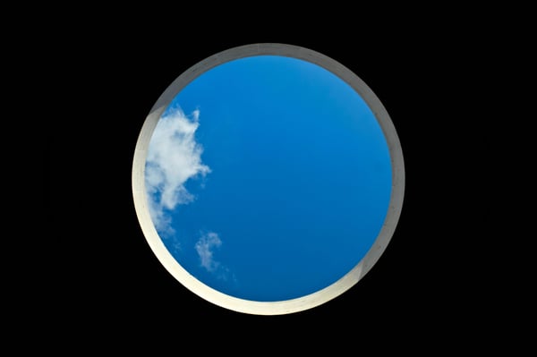 a blue sky with some clouds on the left within a circular shape