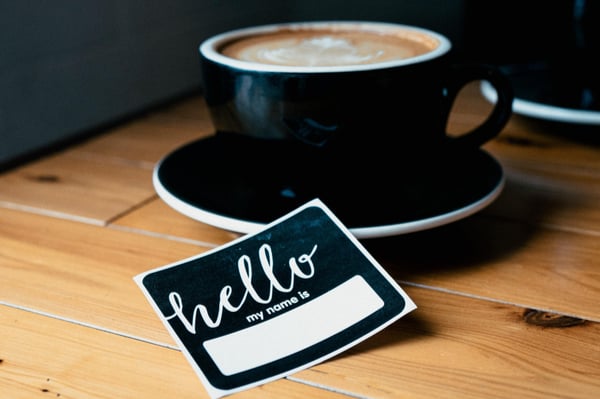 a black teacup with a "hello my name is" sticker laying in front