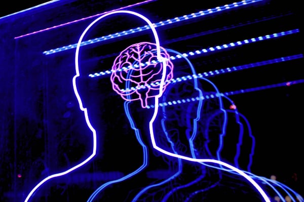 a neon outline of a human head and shoulders with a brain inside the head