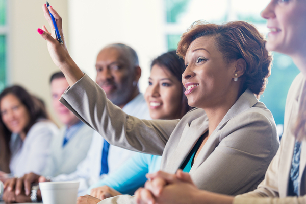 a group of people sitting in a row with a lady raising her hand