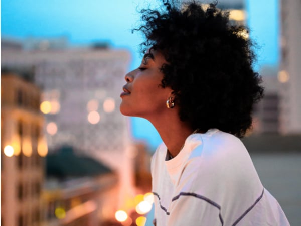 Black woman looking over baclony into city