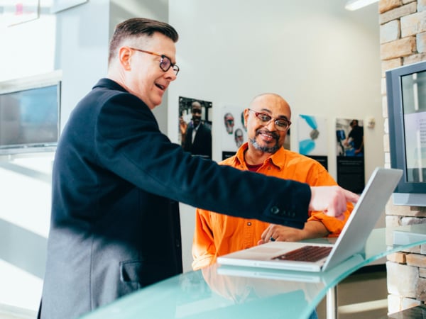 Two people smiling and pointing at laptop screen