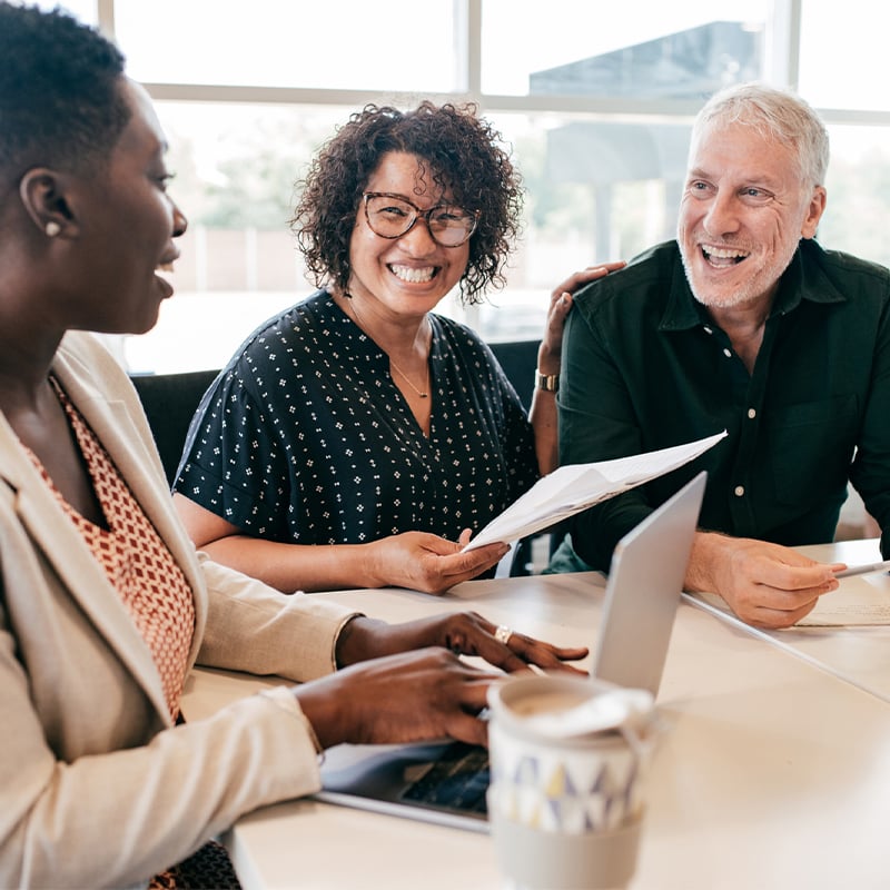 Three people sat around the table smiling