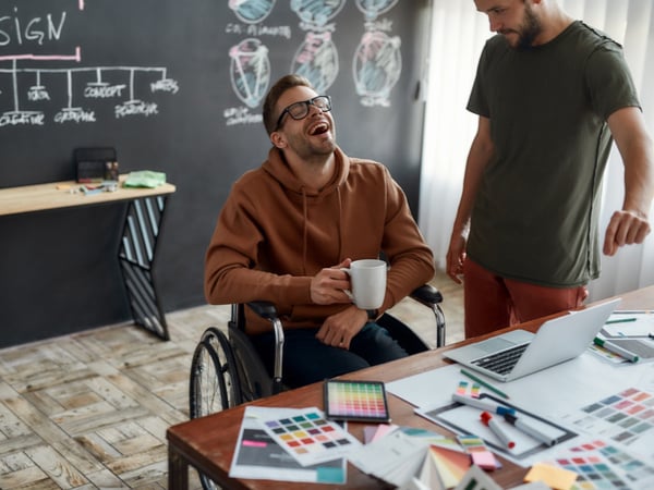 Two colleagues, one in a wheelchair, talking at work
