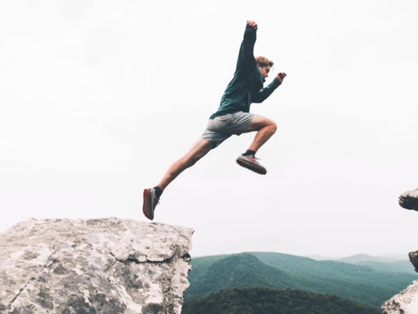 Person leaping between two cliff faces