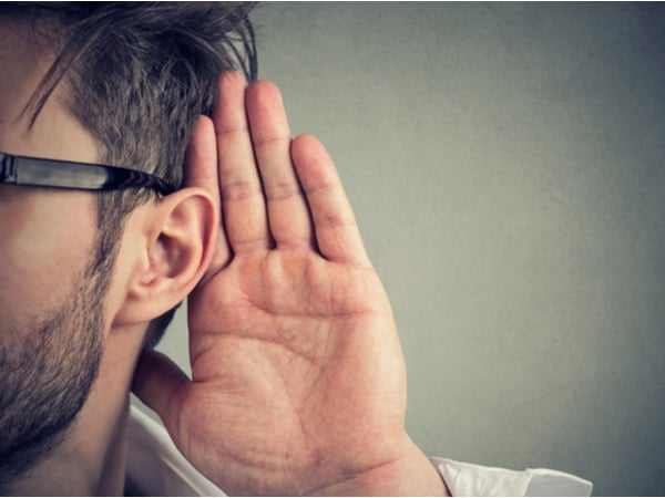 A person listening with their hand to their ear