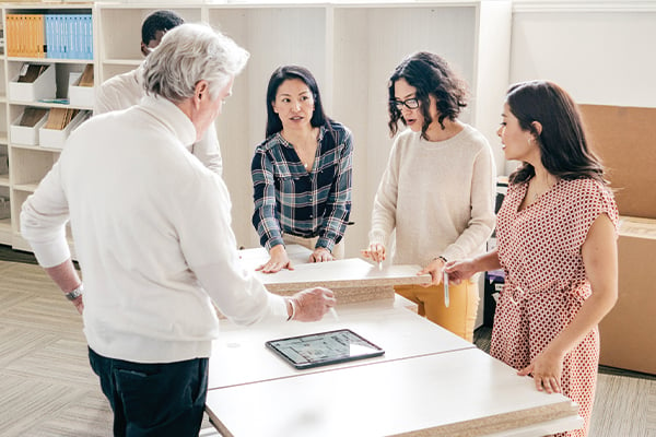 male and female workers around table reviewing laptop