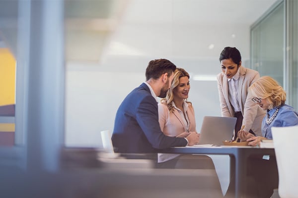 Office workers collaborating around a laptop