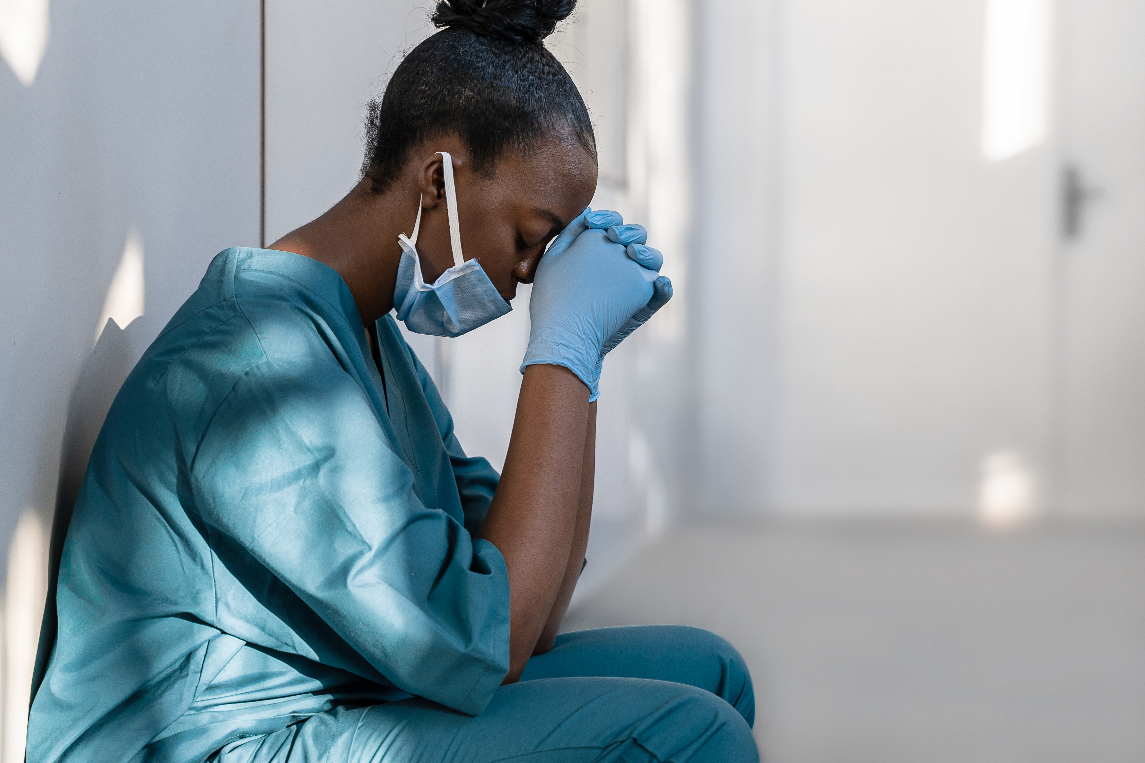 Nurse in PPE with her head in her hands