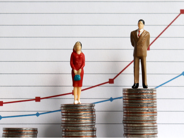 Two figurines (male and female) stand on stacks of coins with differing heights