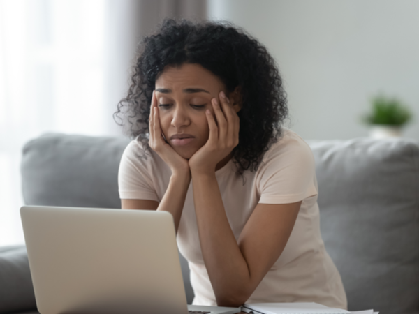 Woman with her head in her hands looking unhappily at her laptop