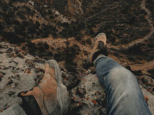 Pair of feet dangling over cliff edge