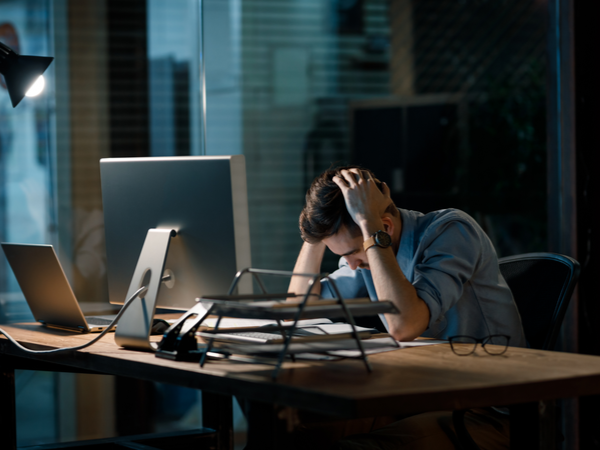 Person at their desk with their head in their hands