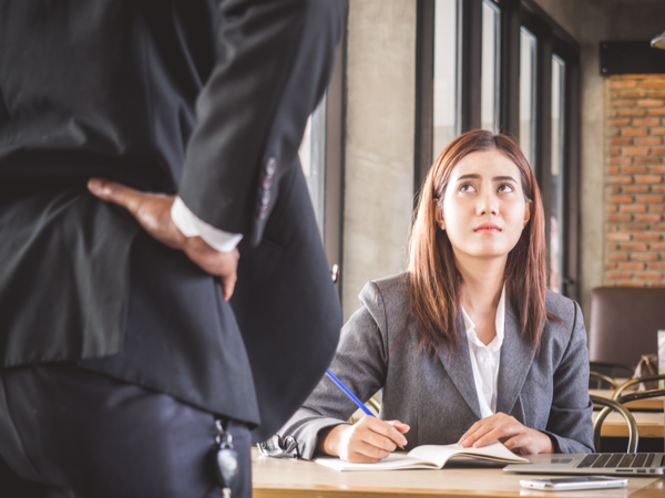 Person at desk looking up sadly at their boss