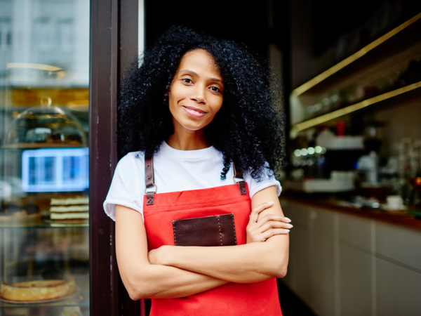 Female business owner stood happily outside business