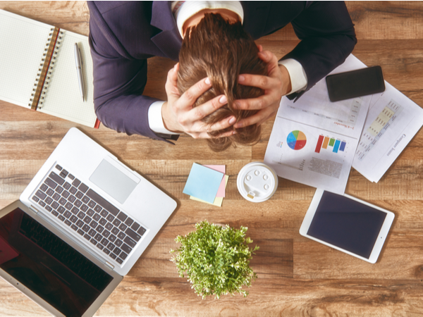 Person with head in their hands at their desk